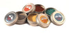 Collection of small metal tins with colorful contents on a white background