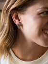 Close-up of eco-friendly triangle stud earrings made from upcycled horn and recycled silver-plated metal by Fair Anita