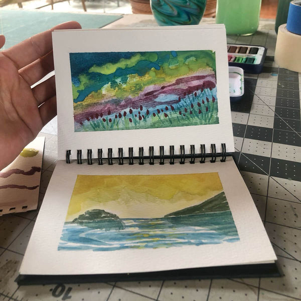 Artist painting on elseware unplug small watercolor paper pad with watercolor paints and brush