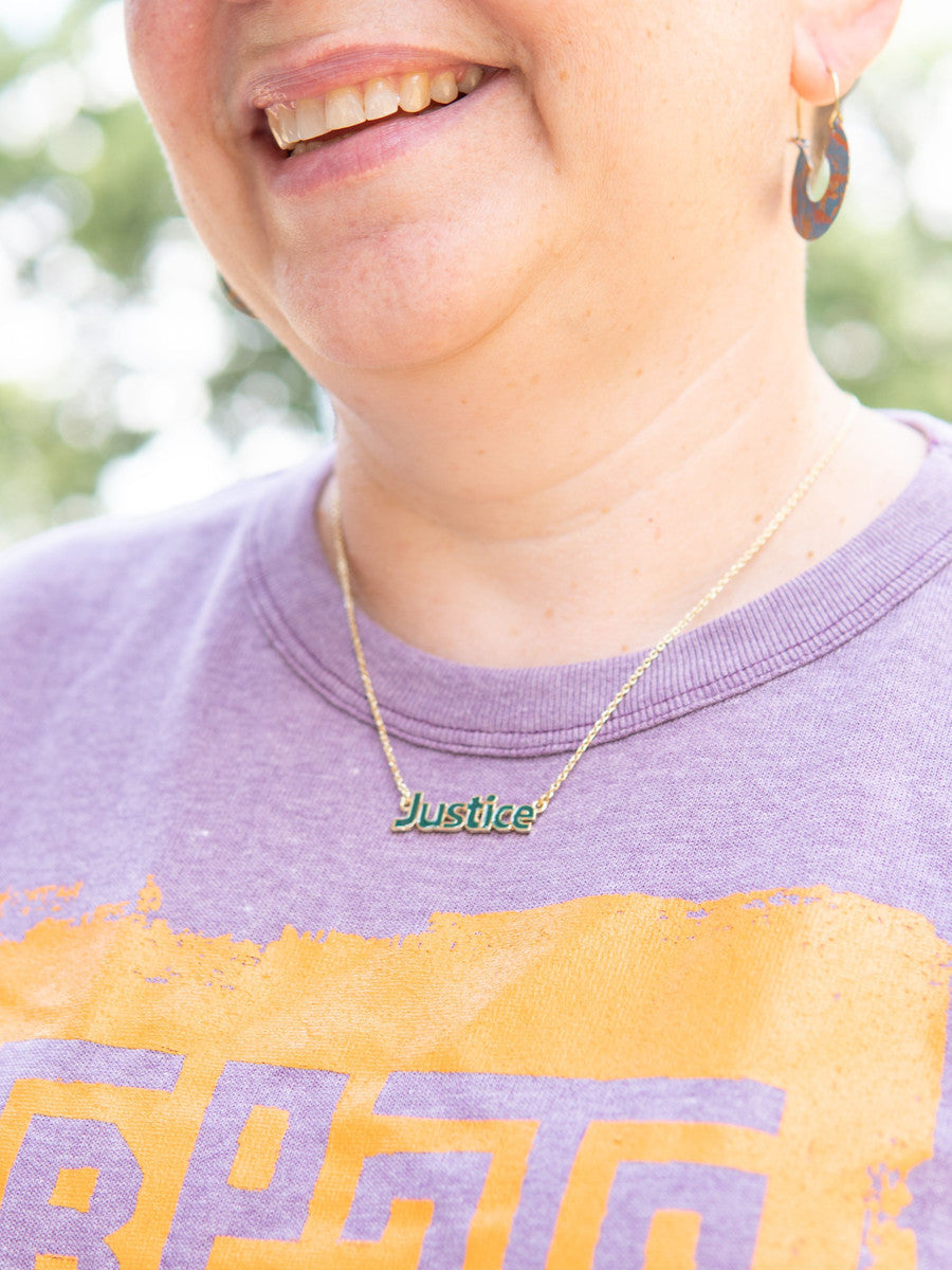 Enameled Justice necklace styled alone showing clean modern word design in dark green enamel