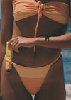 Person wearing a two-tone bikini with a yellow and peach color scheme, holding a yellow object.