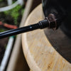 Close-up of a black metal rod with a nut attached to a wooden surface.
