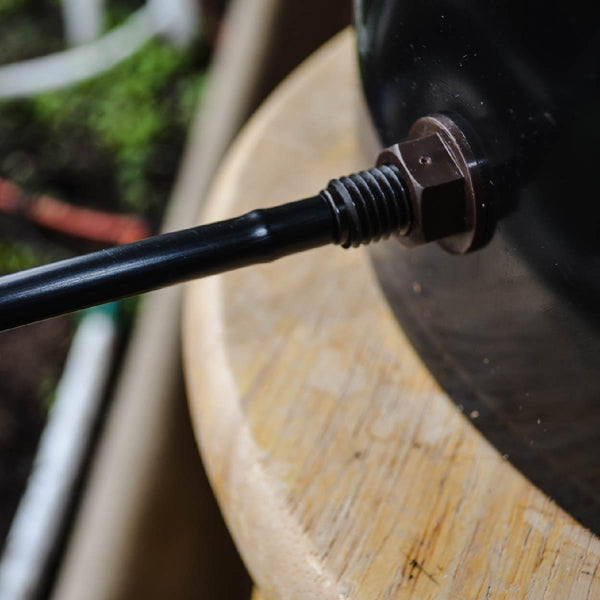 Close-up of a black metal rod with a nut attached to a wooden surface.