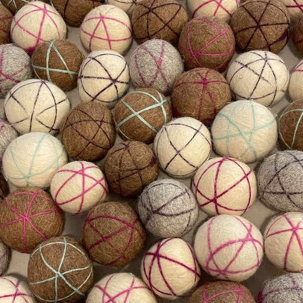 Collection of felted wool balls with patterned strings in various colors.