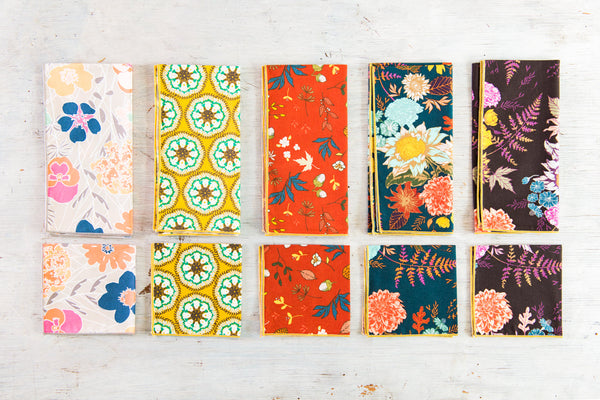 Blue and floral cotton cloth napkins folded and stacked on a wooden board