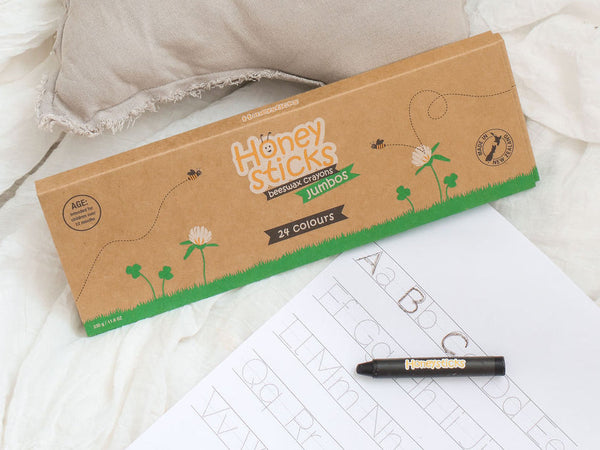 Box of Honey Sticks crayons on a white surface with a coloring book