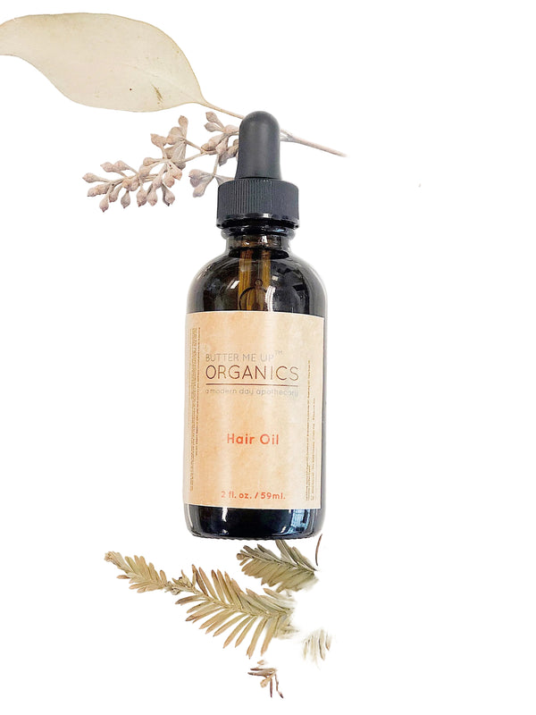 Organic hair oil by Butter Me Up Organics displayed on natural wood surface