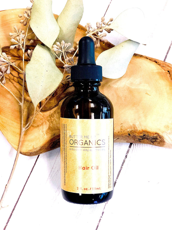 Butter Me Up Organics hair oil with lavender and rosemary essential oils on rustic background