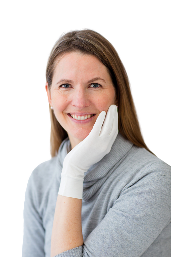 Woman wearing a gray sweater and white gloves against a white background. Remedywear adult eczema & psoriasis gloves with TENCEL & zinc oxide — dermatologist recommended, Oeko-Tex certified & made in Portugal. Heal dry, itchy hands. Shop now.