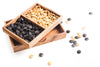 Wooden box with compartments containing black and yellow seeds on a white background