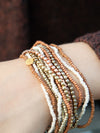 Close-up of gold and peach beaded elastic bracelets from Fair Anita's Burst Bracelet Set