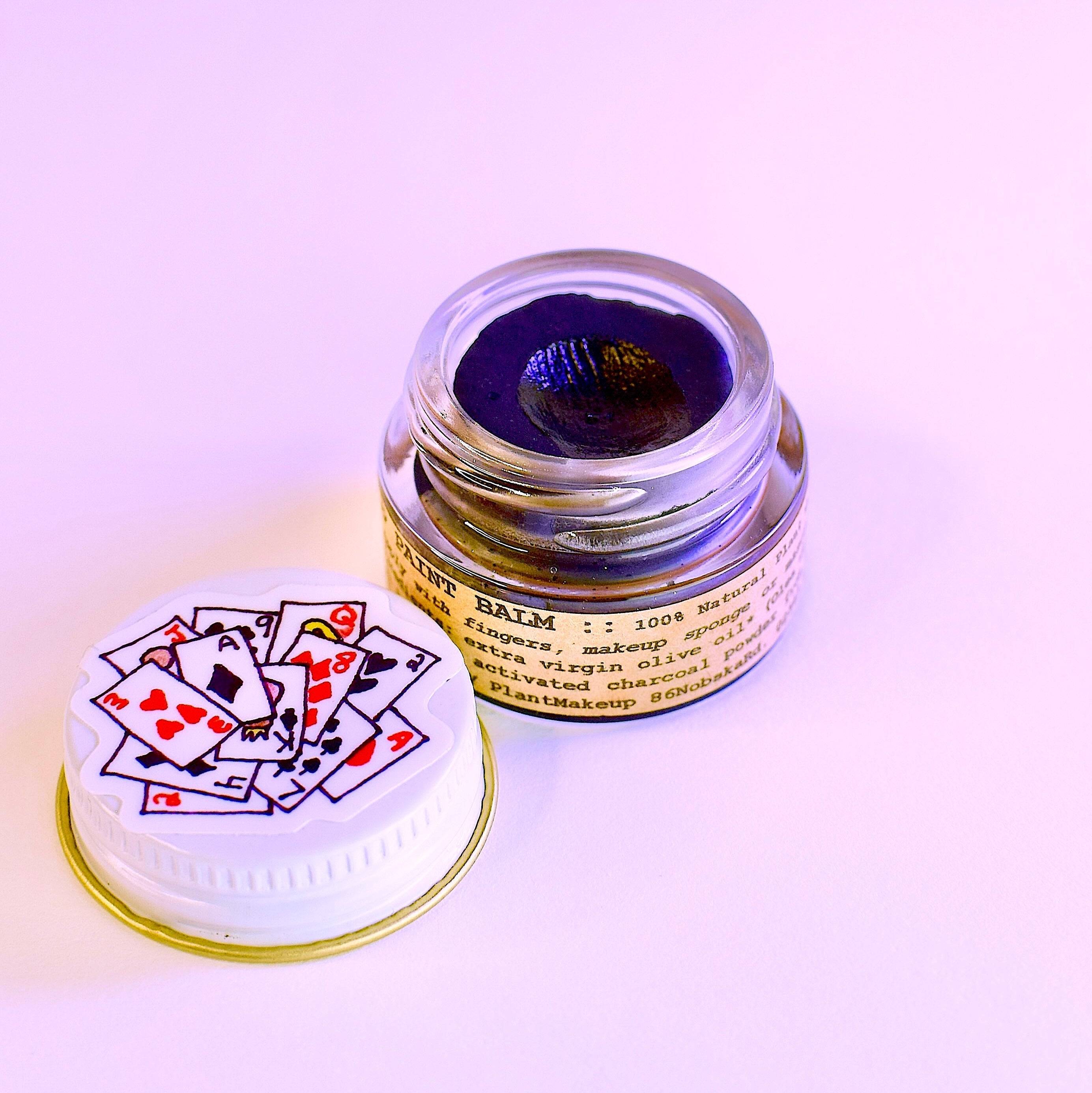 Flat lay of Goth Girl Makeup Balm 1/4oz glass jar with plant-based ingredients including activated charcoal and cocoa butter