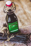 Bottle of vanilla extract with vanilla beans on a wooden surface