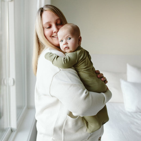 Woman holding a baby in a room with a window
