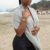 Woman wearing a light gray alpaca knitted scarf on a beach