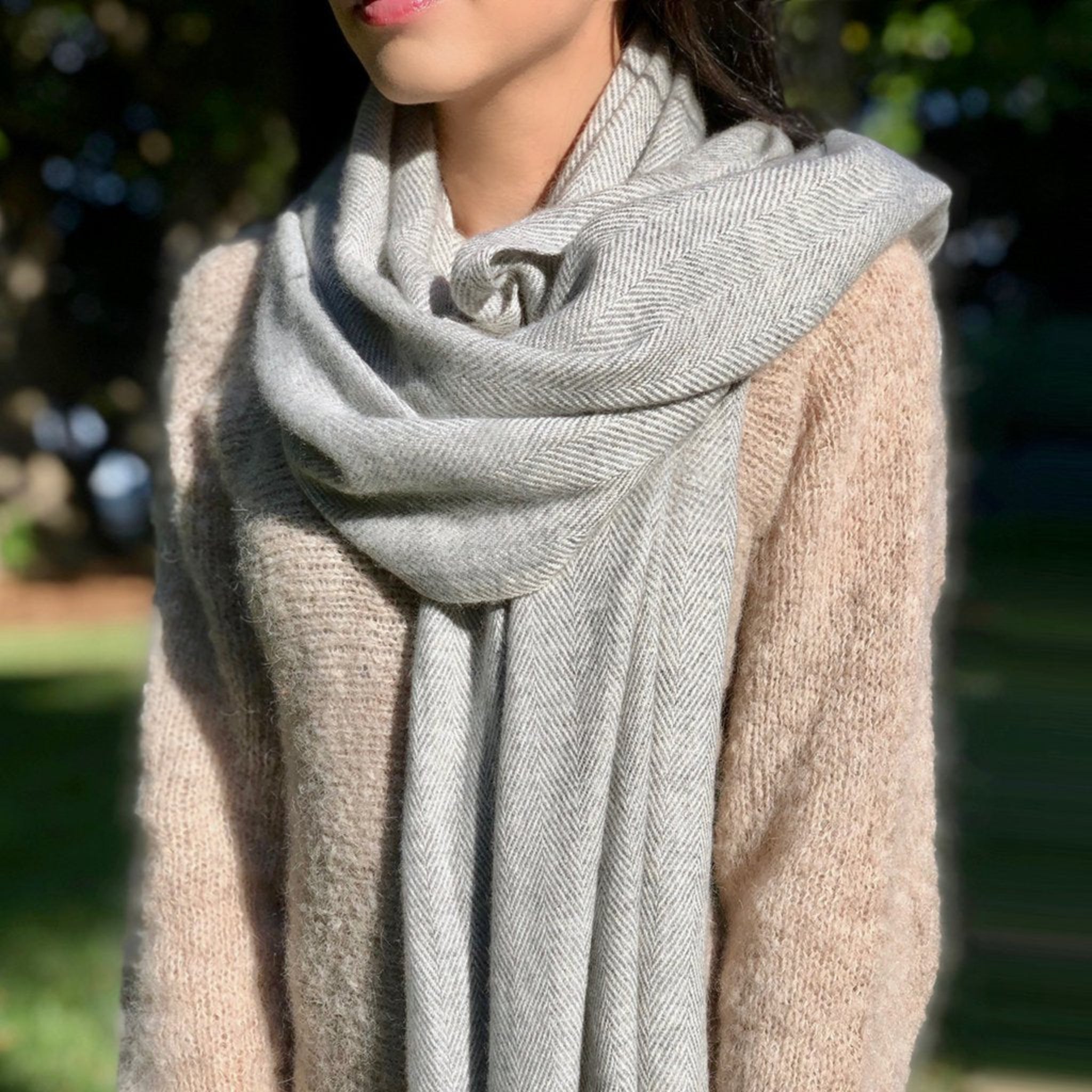 Person wearing a gray scarf with a blurred natural background