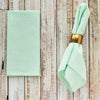 Green seersucker cloth napkins folded and displayed on a wooden table