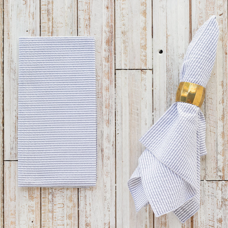 Folded striped napkin with a gold napkin ring on a wooden surface