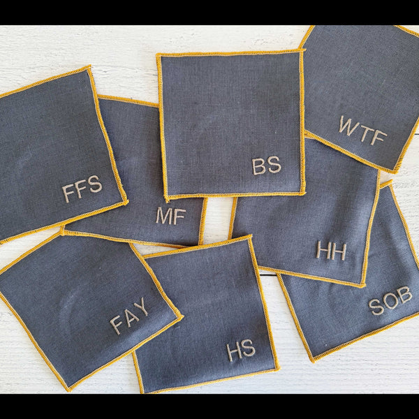 Set of eight grey linen sweary cocktail coasters with deep yellow edging by Dot and Army