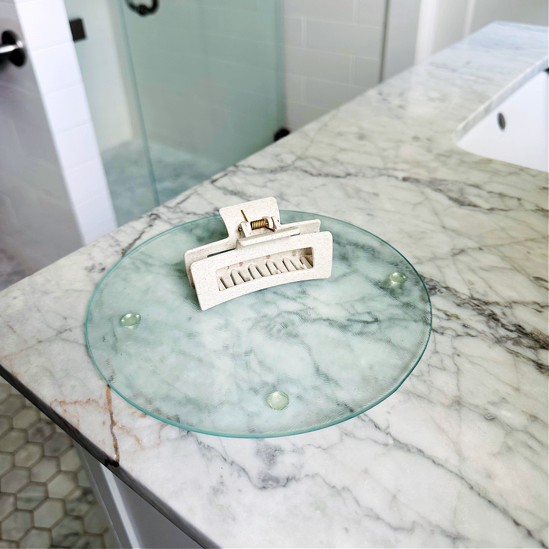 Glass tray with a white hair clip on a marble countertop