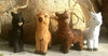 Four animal figurines in black, brown, and white standing in front of a textured wall.