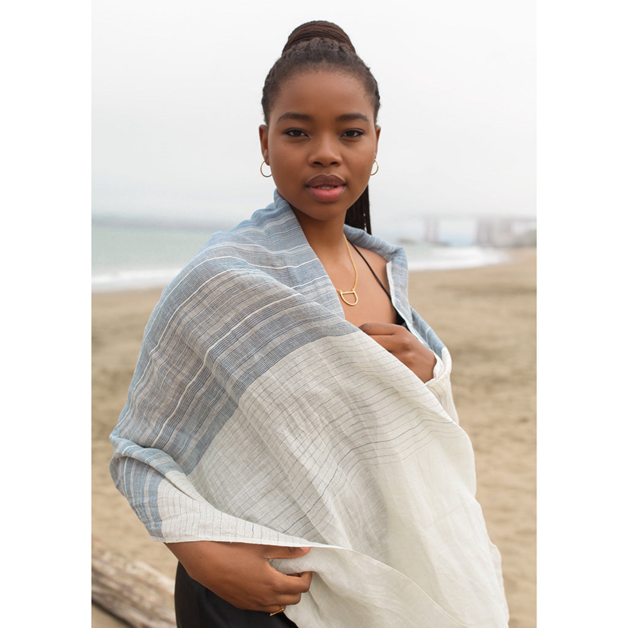 Woman wrapped in a light linen scarf on a beach