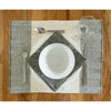 Dining table setting with white plates, silverware, and a glass on a textured placemat.