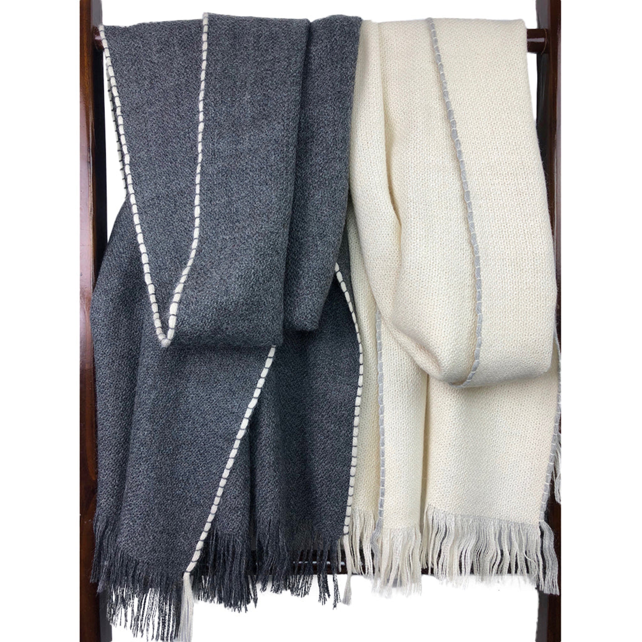 Two scarves, one gray and one white, draped over a wooden rack.