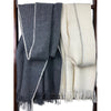 Two scarves, one gray and one white, draped over a wooden rack.