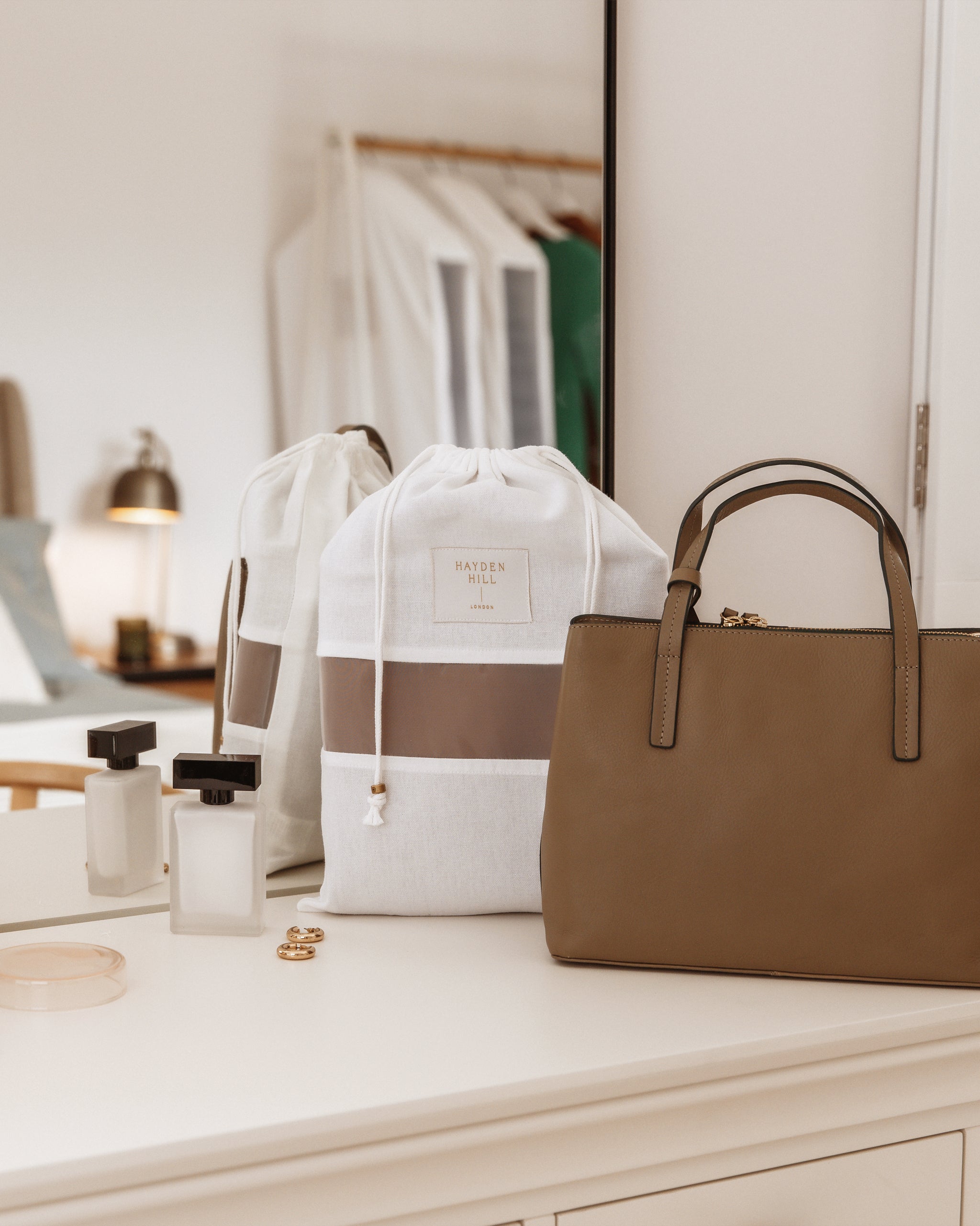 Brown handbag and white tote bag on a dresser with a mirror in the background