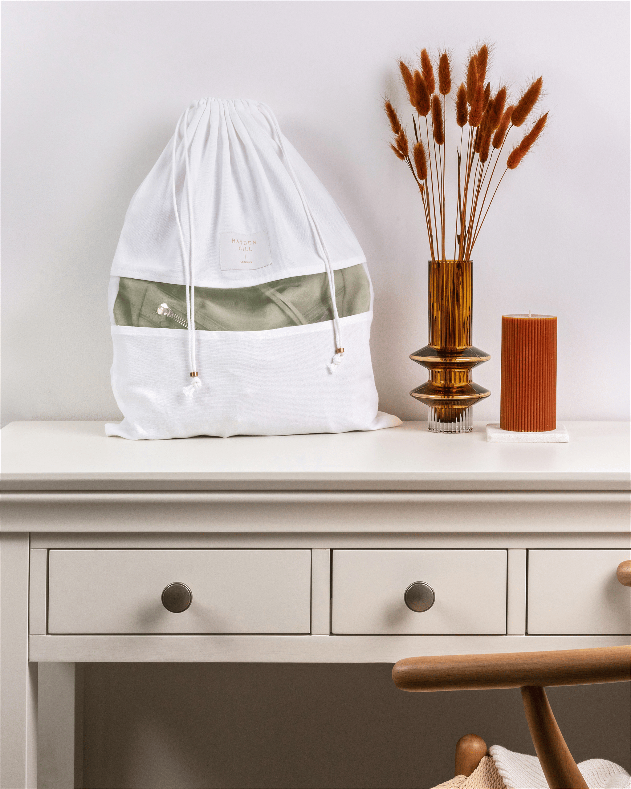 Medium organic cotton dust bag from Hayden Hill displayed on a dresser with dried flowers and candle