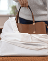 Brown handbag with 'Hayden Hill' label on a white blanket
