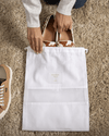 Bird's eye view of shoes being placed into a small Hayden Hill organic cotton dust bag