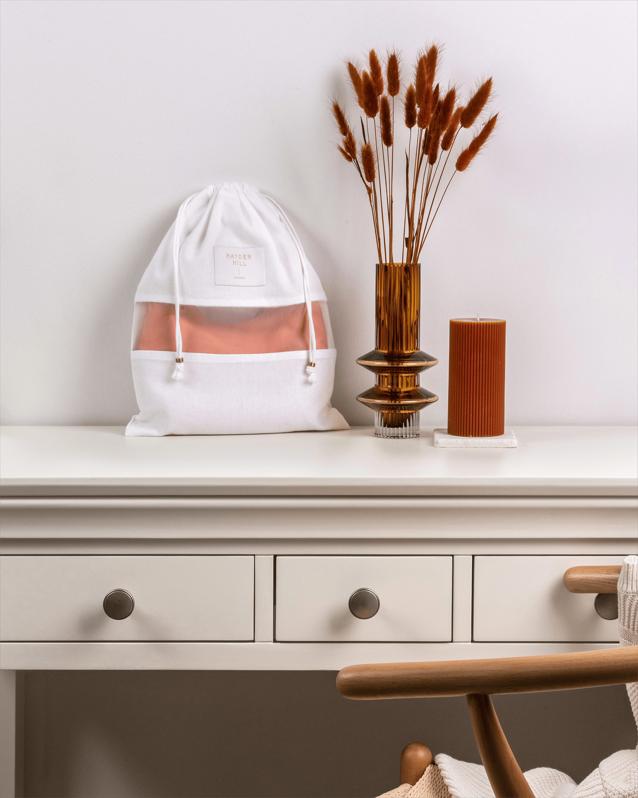 White drawstring bag with a pink interior on a white surface with decorative elements.