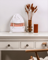 White drawstring bag with a pink interior on a white surface with decorative elements.