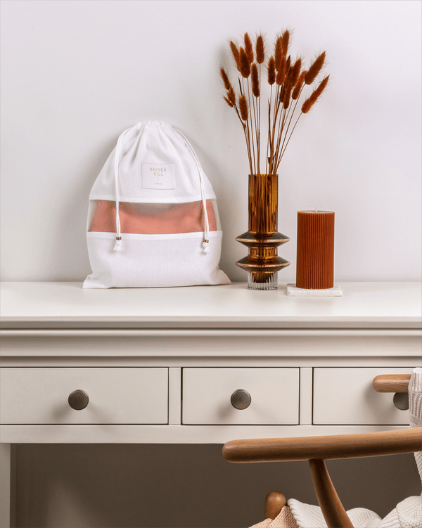 White drawstring bag with a pink interior on a white surface with decorative elements.