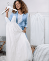 Woman holding white dress on hanger next to a Hayden Hill long organic hanging garment bag