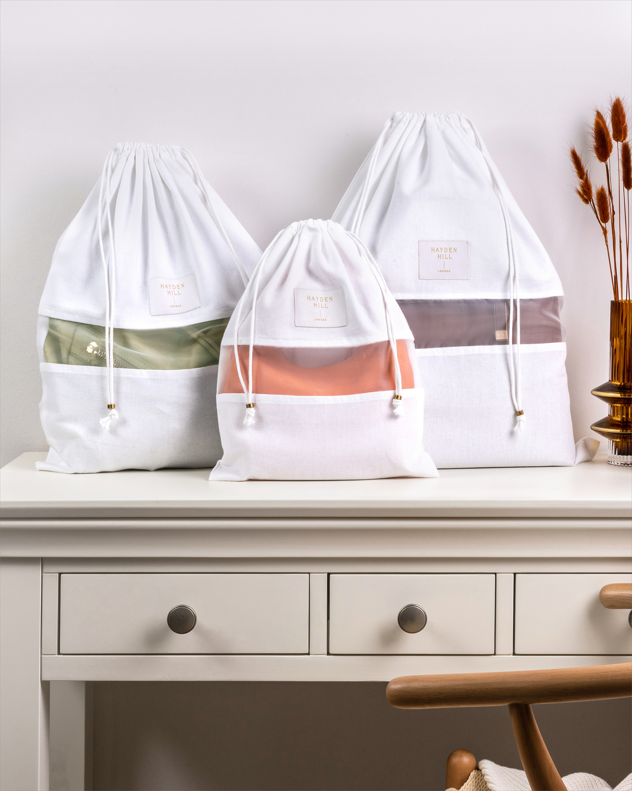 Set of three Hayden Hill organic cotton dust bags displayed on a dresser in small, medium and large sizes