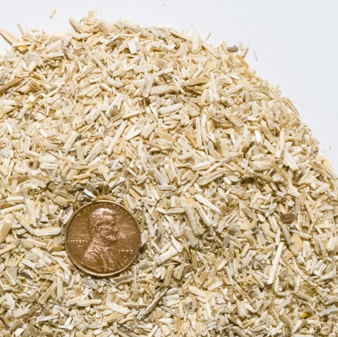 Close-up of dried herbs with a penny for scale on a white background