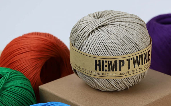 Ball of hemp twine with a label, surrounded by other colored balls on a neutral background
