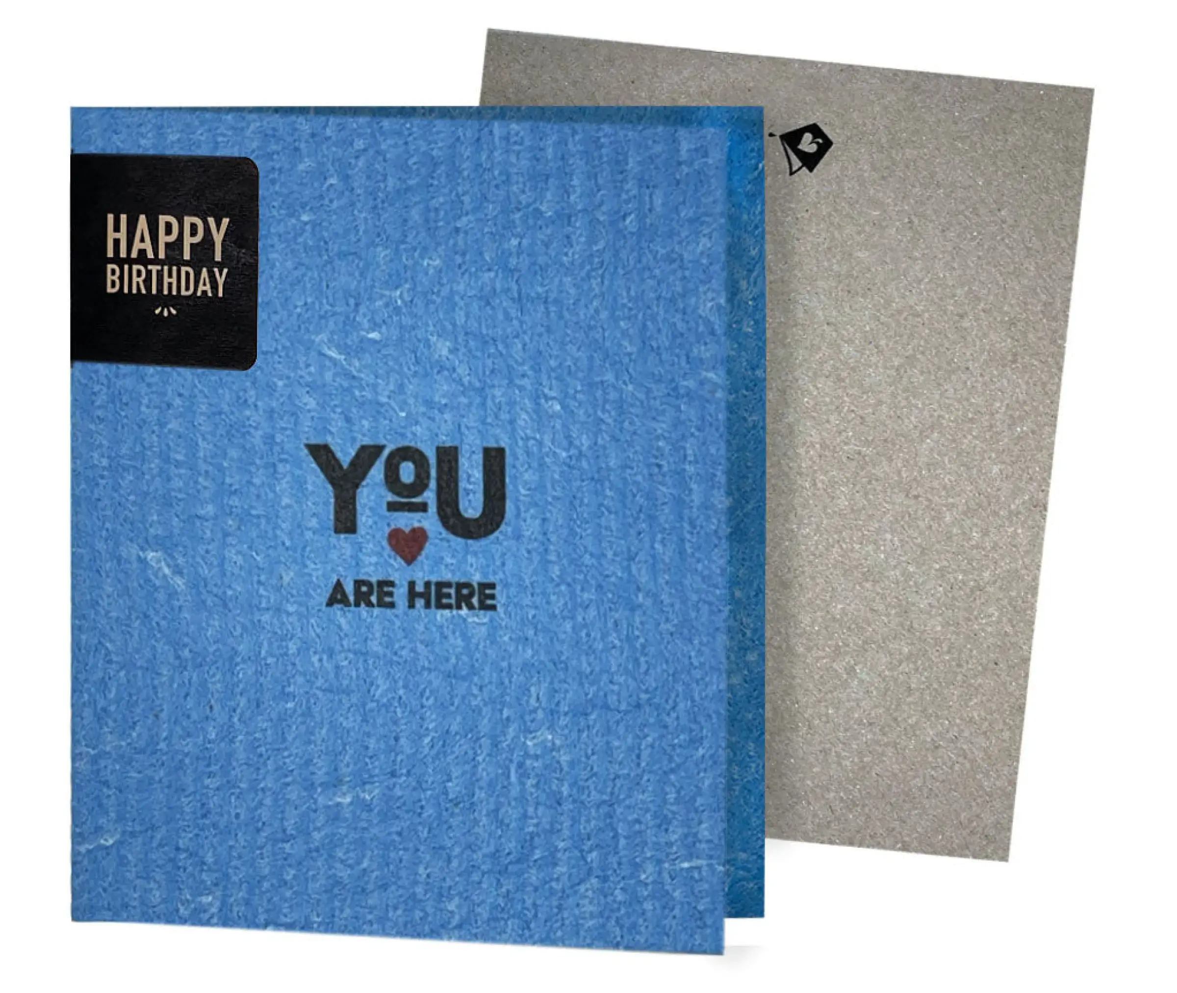 A blue eco-friendly greeting card with a red heart and the phrase 'YOU ARE HERE' printed on it, alongside a grey envelope.