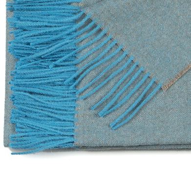Close-up of a rug with blue fringe on a gray background