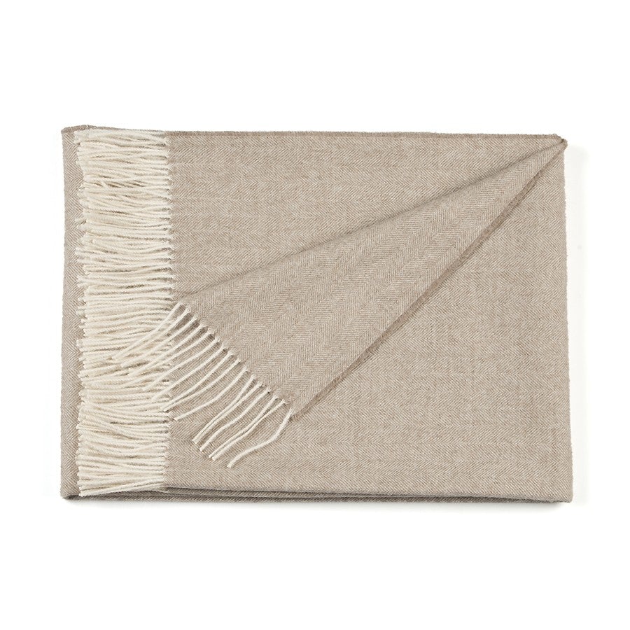 Beige throw blanket with white fringe on a white background