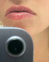 Close-up of a person's lips with a blurred phone camera in the foreground