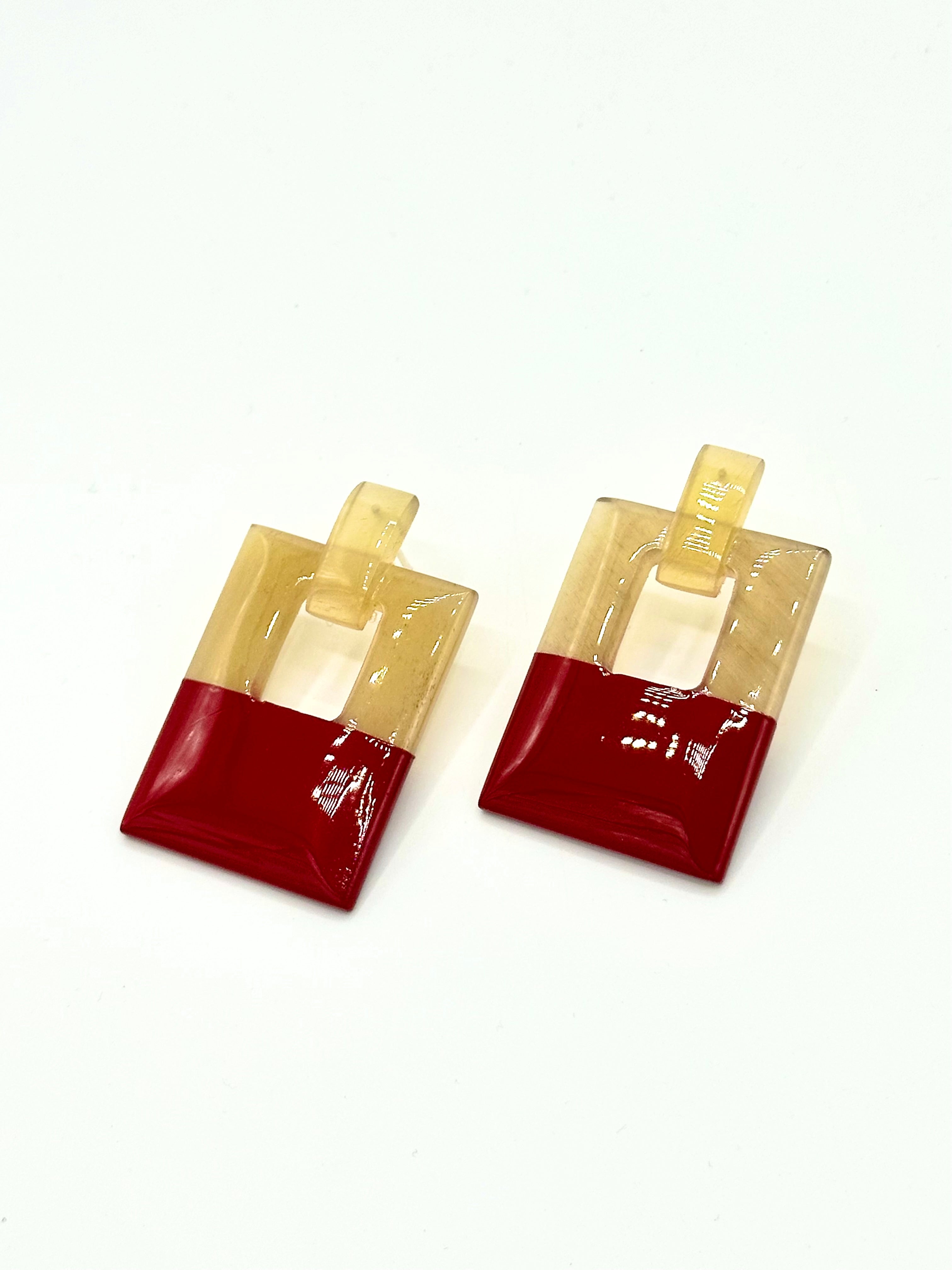 Pair of earrings with red and beige square design on a white background