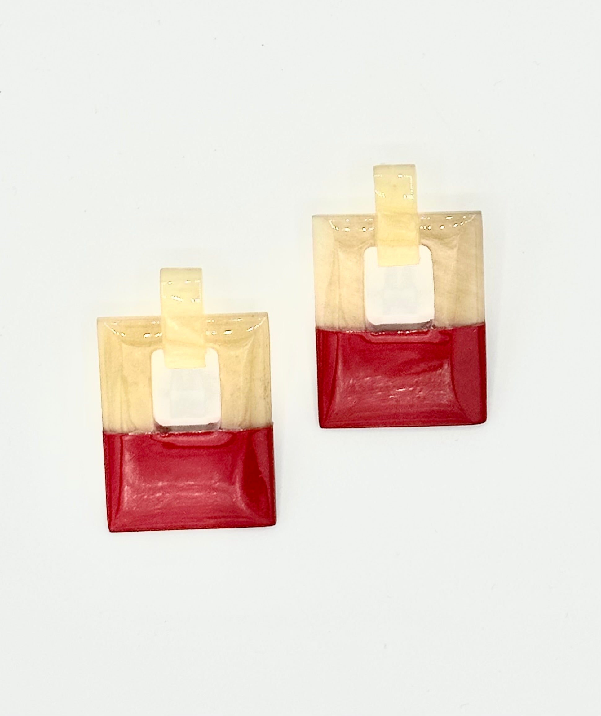 Pair of square-shaped earrings with red and beige color block design on a white background