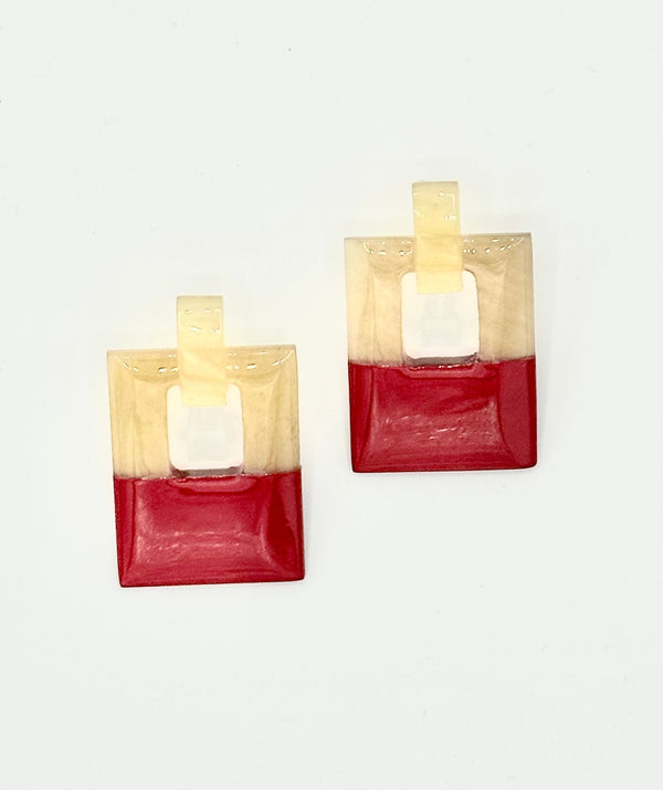 Pair of square-shaped earrings with red and beige color block design on a white background