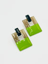 Two green square earrings with black and white accents on a light gray background