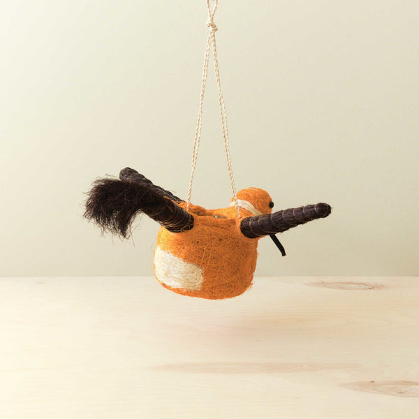 Textured orange bird-shaped ornament hanging on a beige background