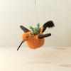 Hanging planter shaped like a bird with a small plant inside on a light background